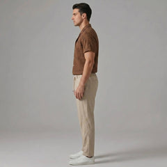 Side view of man in coffee brown jacquard Cuban shirt and crinkle straight leg pants on plain background