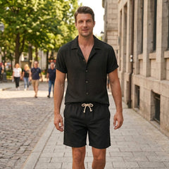 Man in coffee brown textured Cuban shirt and linen drawstring shorts in warm sunny outdoor scene
