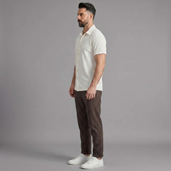 Side view of man in coffee brown waffle button up shirt and straight leg linen pants