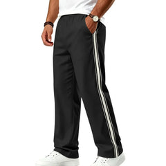 Man wearing MannerCo black color-block jogger pants with contrast tape detail, side view