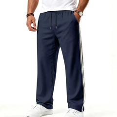 Man wearing MannerCo navy blue color-block drawstring jogger pants with contrast tape detail, front view
