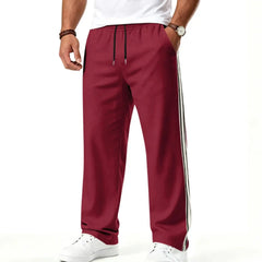 Man wearing MannerCo wine red color-block jogger pants with contrast tape detail, side view
