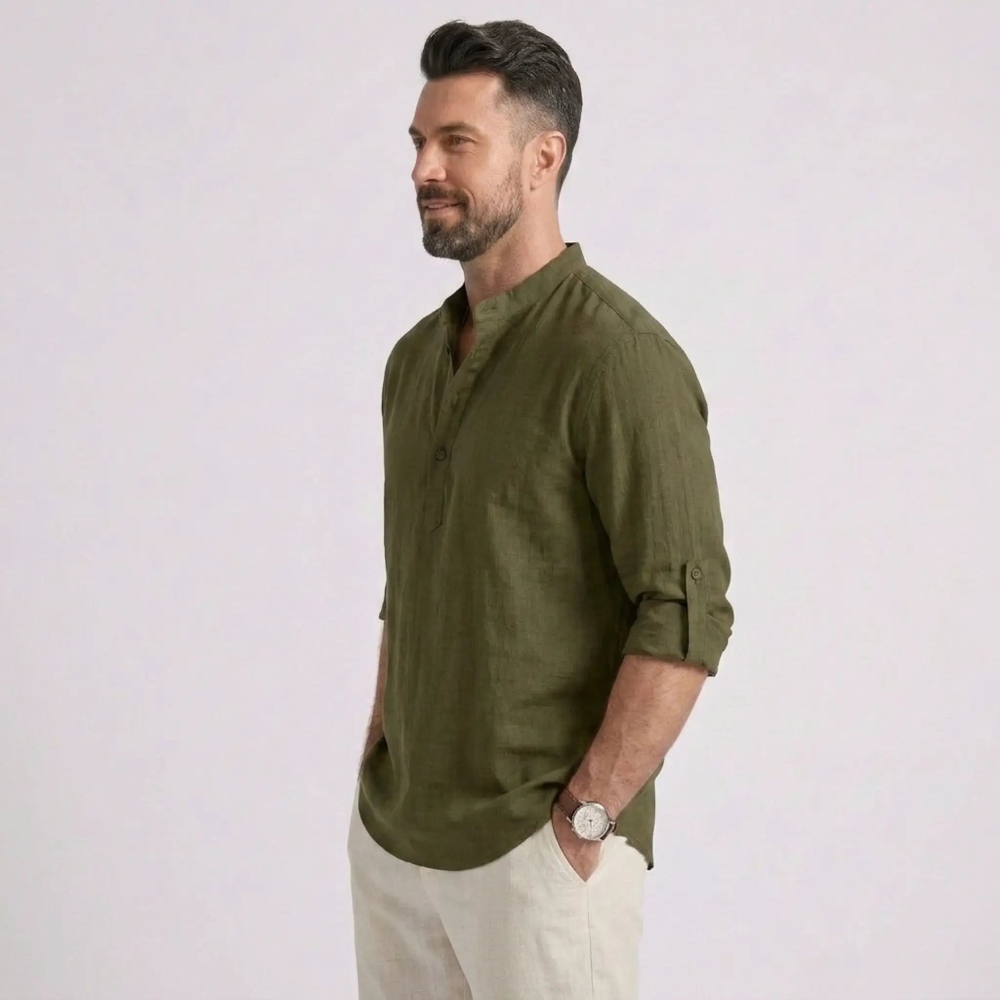 Man wearing MannerCo army green cotton linen long sleeve Henley shirt, side view on plain background