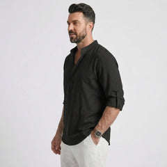 Man wearing MannerCo black cotton linen long sleeve Henley shirt, side view on plain background