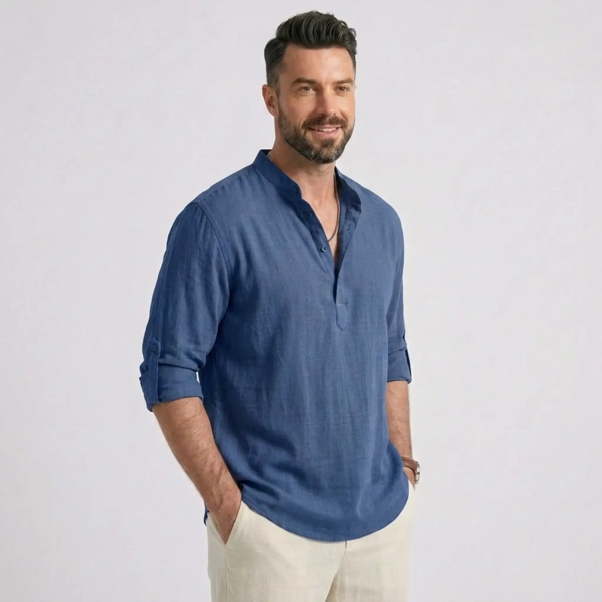 Man wearing MannerCo denim blue cotton linen long sleeve Henley shirt, side view on plain background