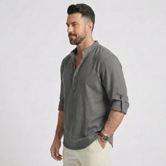 Man wearing MannerCo grey cotton linen long sleeve Henley shirt, side view on plain background