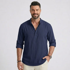Man wearing MannerCo navy cotton linen long sleeve Henley shirt, side view on plain background