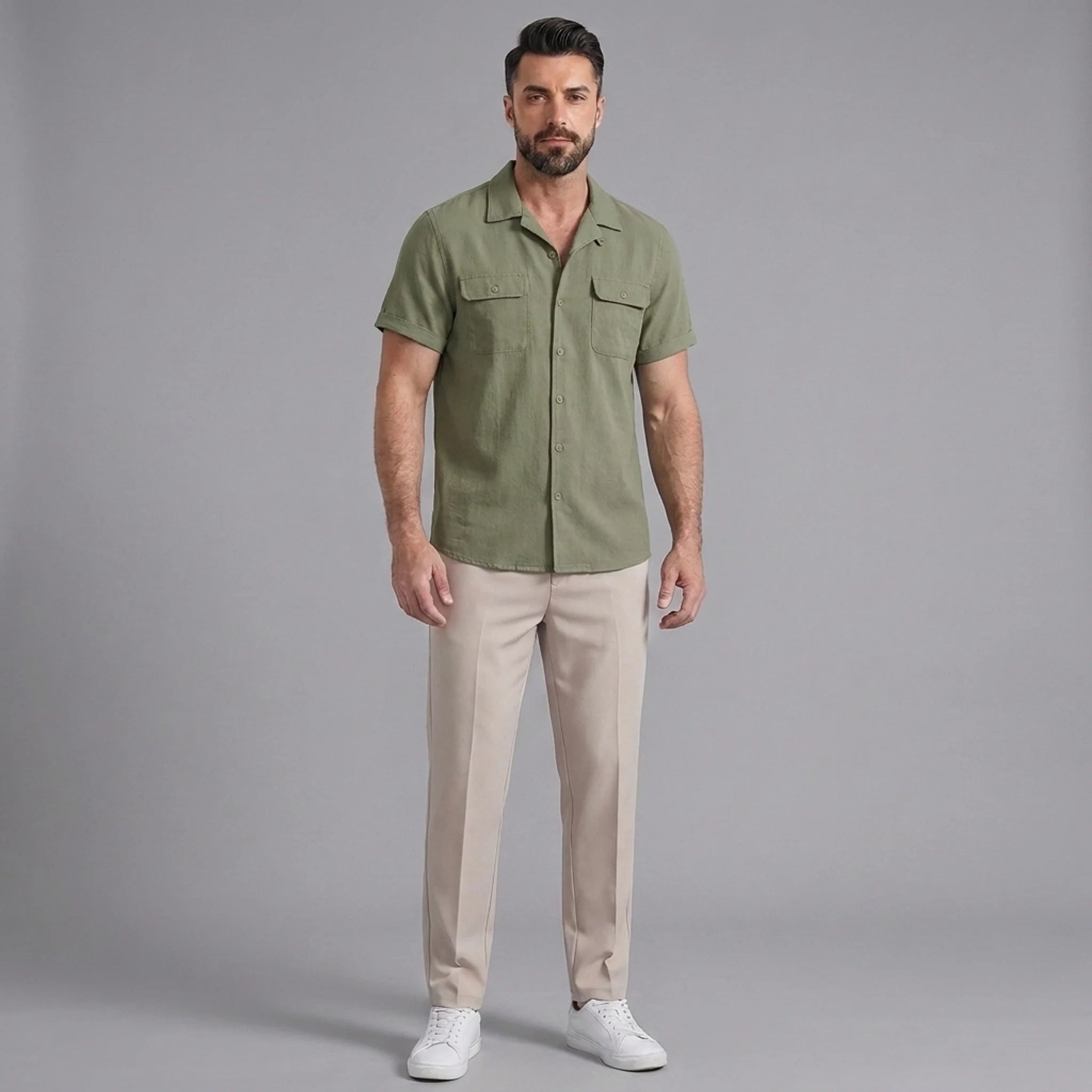 Man wearing a dark green linen Cuban collar shirt and slim fit tapered trousers front view on plain background