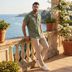 Man wearing dark green linen Cuban collar shirt and slim fit tapered trousers in outdoor lifestyle setting