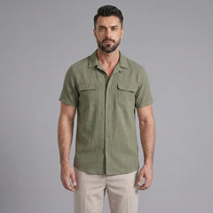 Three quarter view of man in dark green linen Cuban collar shirt and slim fit tapered trousers