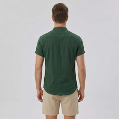 Back view of man wearing dark green linen look stand collar shirt and crinkle drawstring shorts
