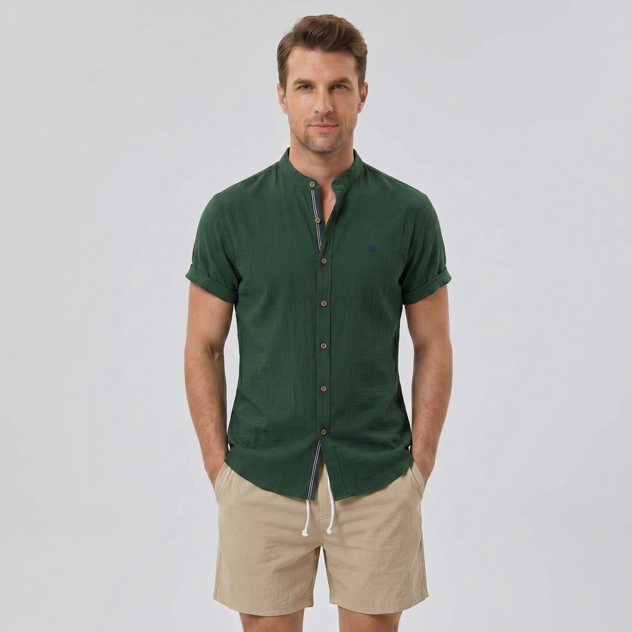 Man wearing a dark green linen look stand collar shirt and crinkle textured drawstring shorts front view