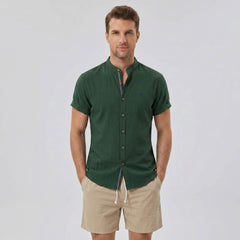 Man wearing a dark green linen look stand collar shirt and crinkle textured drawstring shorts front view