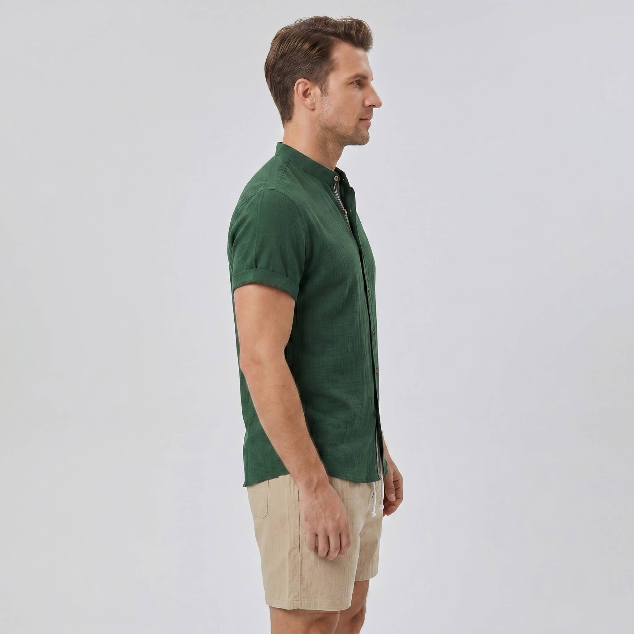 Side view of man in dark green linen look stand collar shirt and crinkle textured drawstring shorts