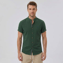 Three quarter view of man in dark green linen look stand collar shirt and crinkle drawstring shorts
