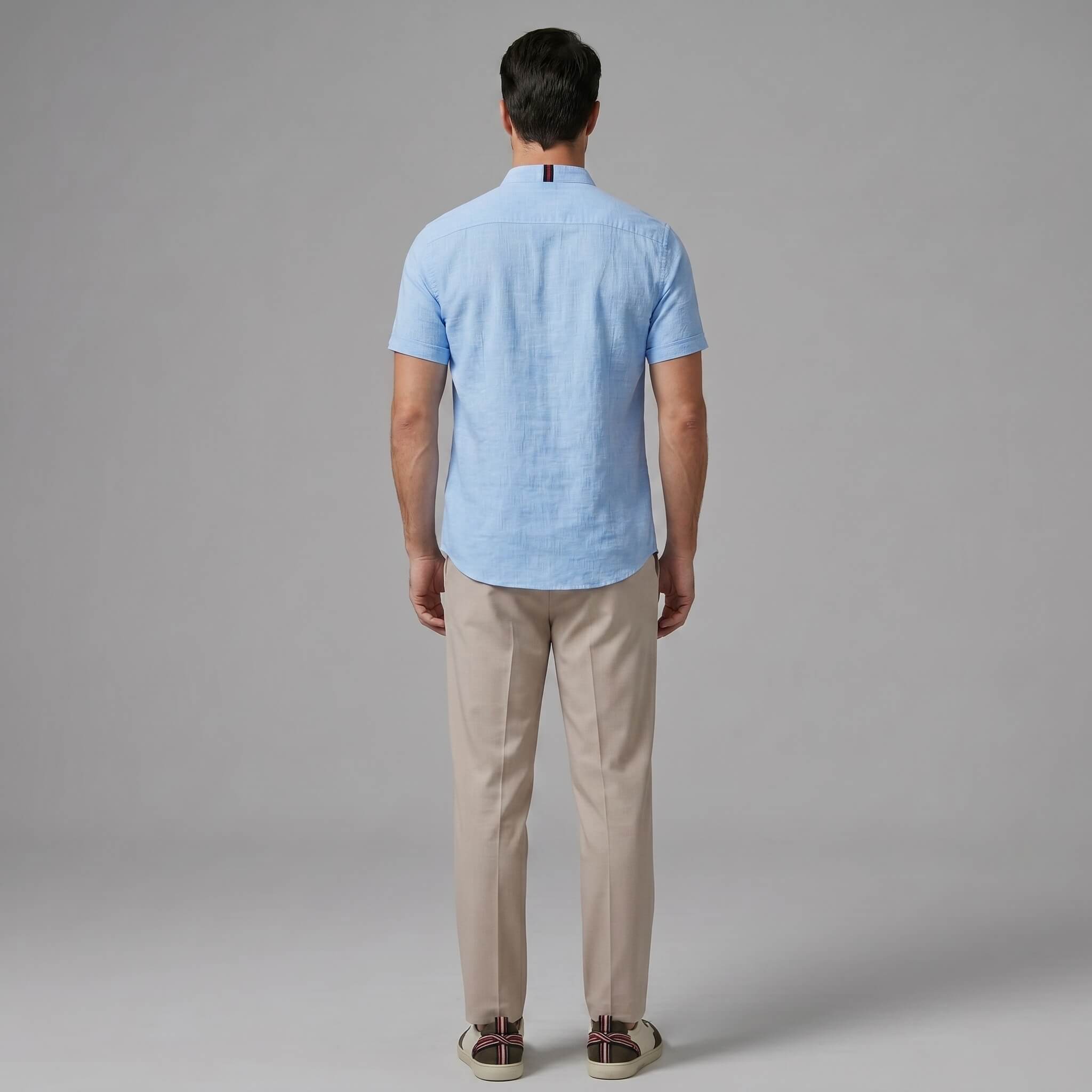 Man in dark green linen look stand collar shirt and tapered trousers in outdoor summer lifestyle