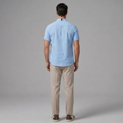Man in dark green linen look stand collar shirt and tapered trousers in outdoor summer lifestyle