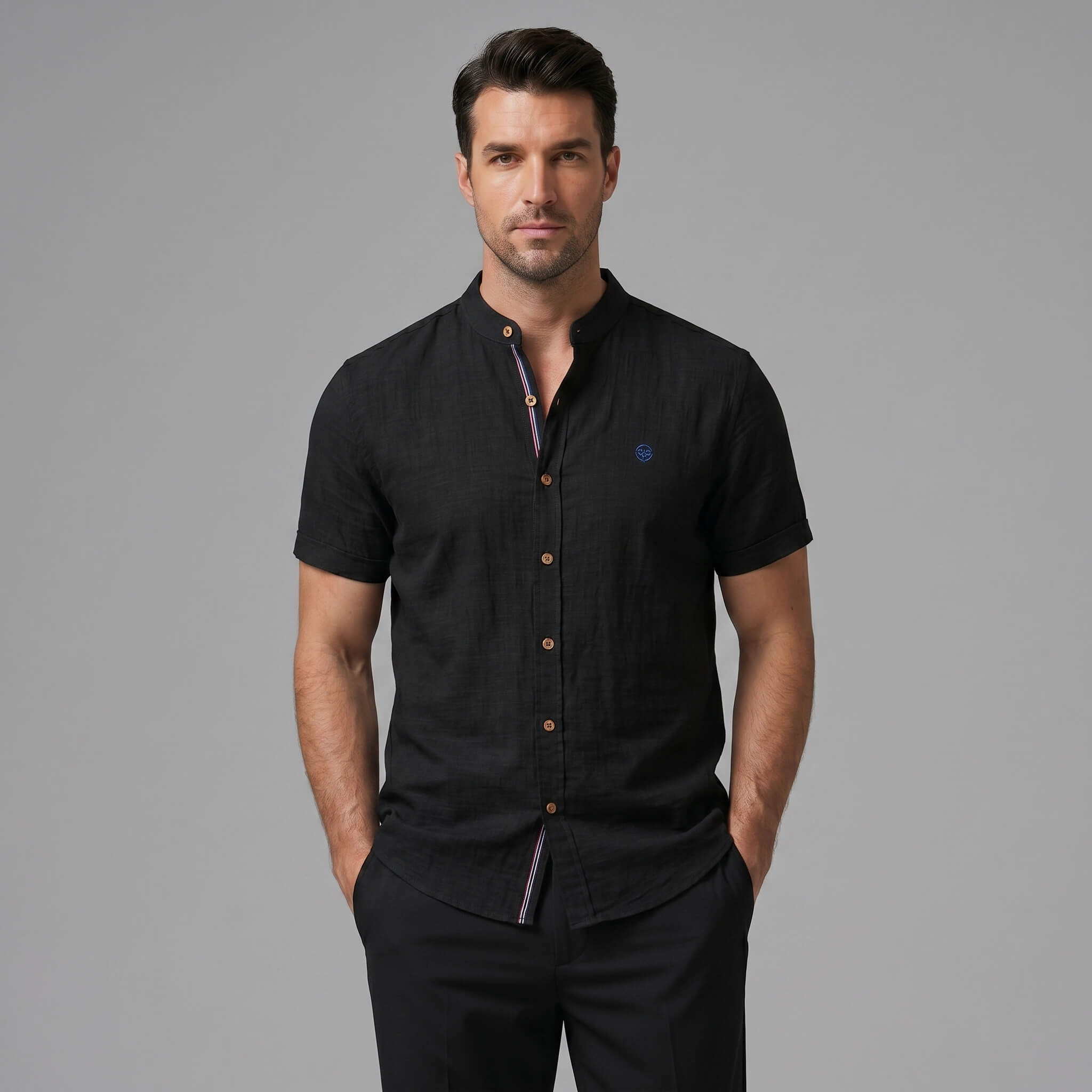 Three quarter view of man in dark green linen look stand collar shirt and slim tapered trousers