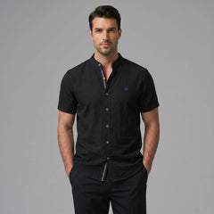Three quarter view of man in dark green linen look stand collar shirt and slim tapered trousers