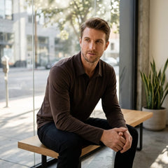 Man wearing dark green solid long sleeve cotton polo shirt in outdoor lifestyle setting