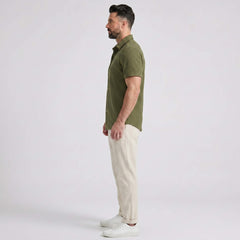 Side view of man in dark green waffle button up shirt and straight leg linen pants