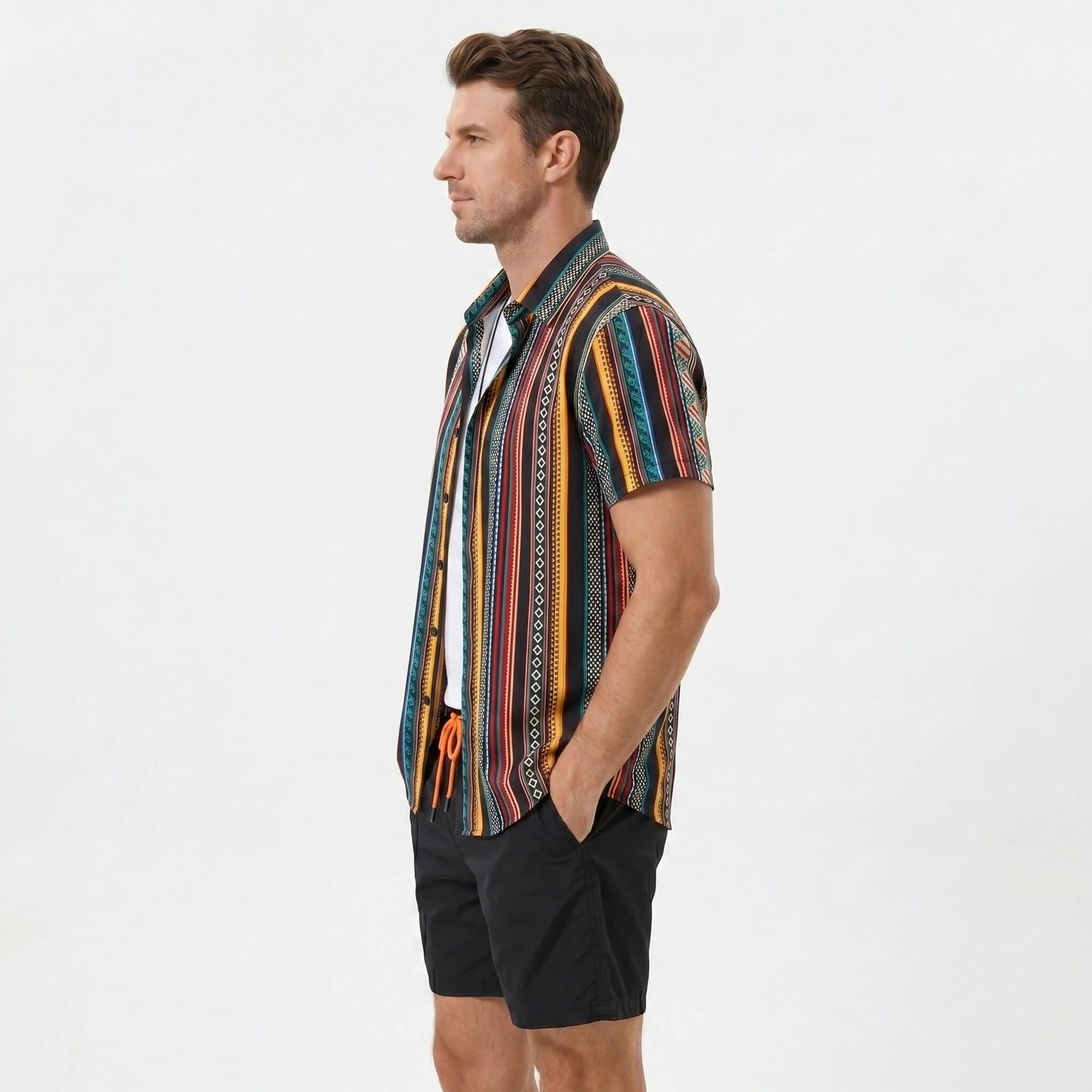 Side view of man in ethnic geometric print button up shirt and swim shorts on plain background