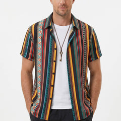Three quarter view of man in ethnic geometric print shirt and swim shorts on plain background