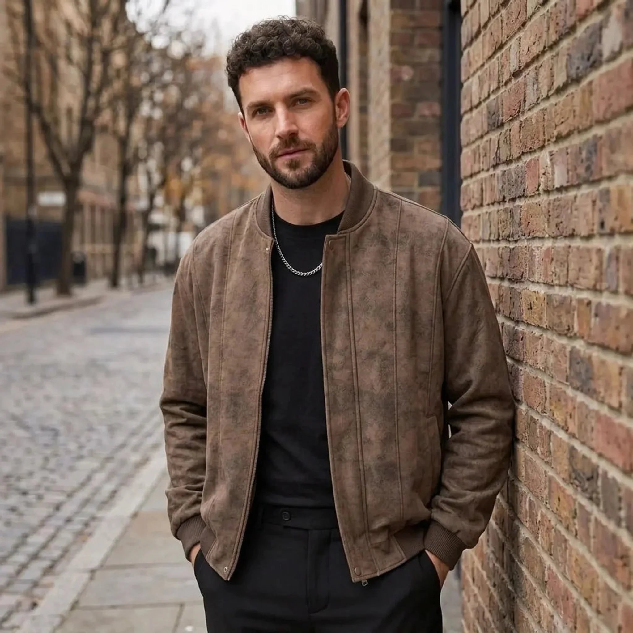 Man wearing MannerCo coffee faux suede bomber jacket on cobblestone street