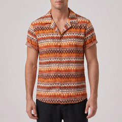 Man wearing a patterned orange and brown shirt against a plain background