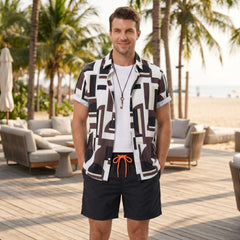 Man in geometry colorblock print shirt and swim shorts walking in sunny outdoor beach setting