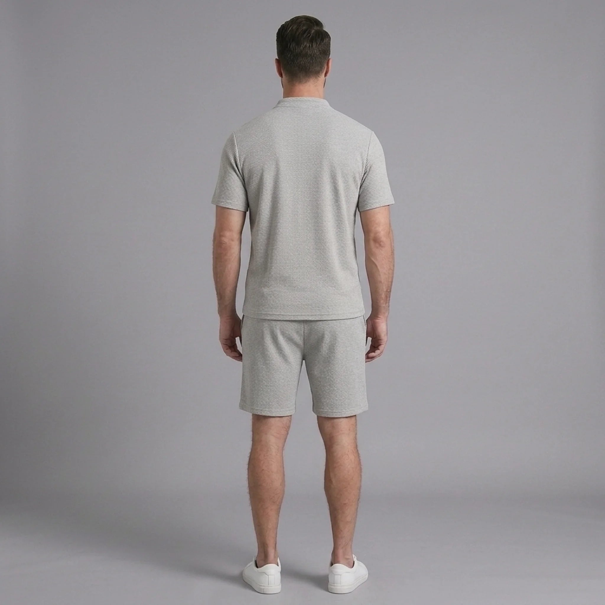 Back view of man wearing grey waffle stand collar shirt and drawstring shorts