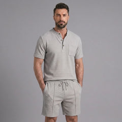 Man wearing a grey waffle stand collar button up shirt and drawstring shorts front view