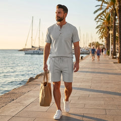 Man in grey waffle stand collar shirt and drawstring shorts in sunny outdoor summer scene