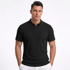 Man wearing MannerCo black jacquard knit polo shirt with button placket and classic collar, front view