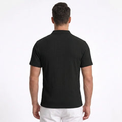 Man wearing MannerCo black jacquard knit polo shirt in outdoor lifestyle setting