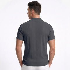 Man wearing MannerCo navy blue jacquard knit polo shirt in outdoor lifestyle setting