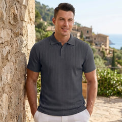 Man wearing MannerCo navy blue jacquard knit polo shirt in outdoor lifestyle setting