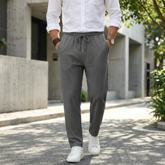 Man wearing MannerCo army green jacquard ribbed straight leg drawstring trousers, back view on plain background