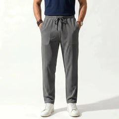 Man wearing MannerCo army green jacquard ribbed straight leg drawstring trousers, front view on plain background