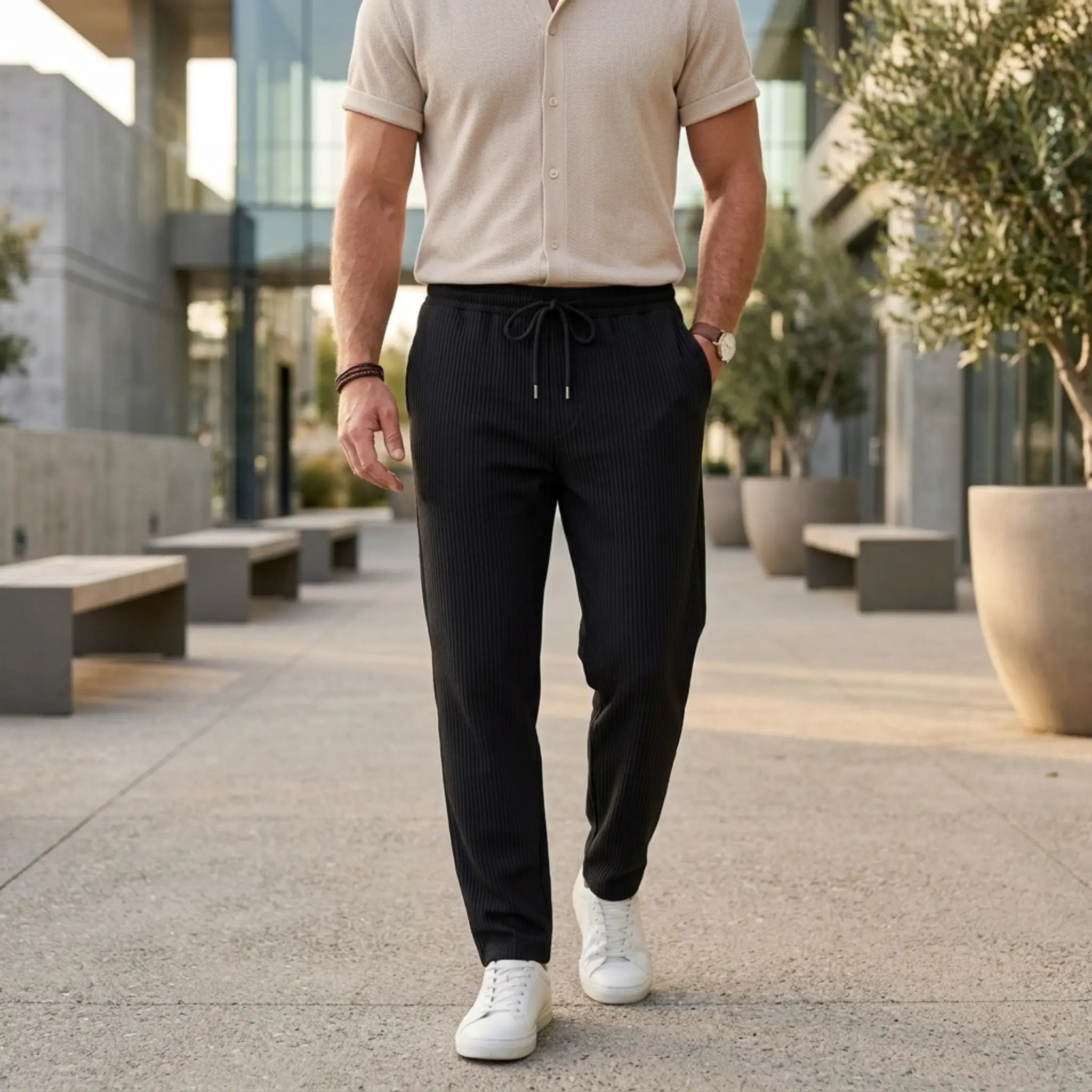 Man wearing MannerCo black jacquard ribbed straight leg drawstring trousers, front view on plain background