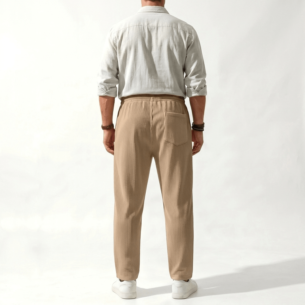 Man wearing MannerCo dark gray jacquard ribbed straight leg drawstring trousers, side view on plain background