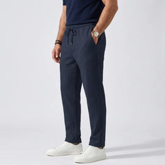 Man wearing MannerCo khaki jacquard ribbed straight leg drawstring trousers, front view on plain background