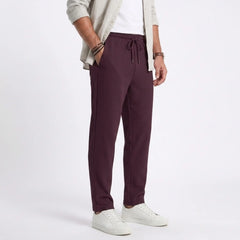 Man wearing MannerCo light gray jacquard ribbed straight leg drawstring trousers, front view on plain background