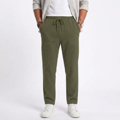 Man wearing MannerCo light gray jacquard ribbed straight leg drawstring trousers in outdoor lifestyle setting