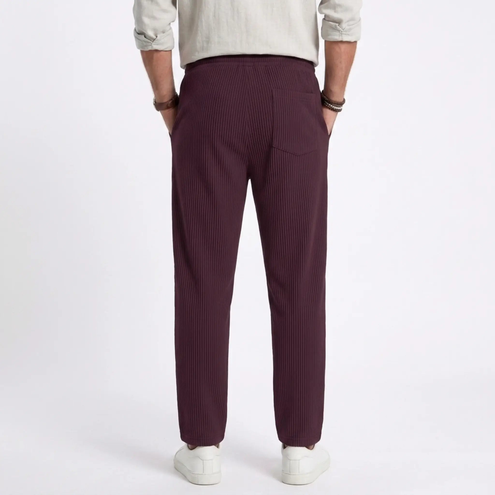 Man wearing MannerCo light gray jacquard ribbed straight leg drawstring trousers, side view on plain background