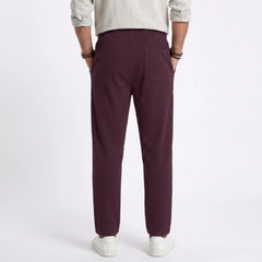 Man wearing MannerCo light gray jacquard ribbed straight leg drawstring trousers, side view on plain background