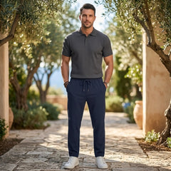Man wearing MannerCo navy jacquard ribbed drawstring trousers, side view on plain background