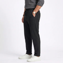 Man wearing MannerCo white jacquard ribbed straight leg drawstring trousers outdoors in urban setting