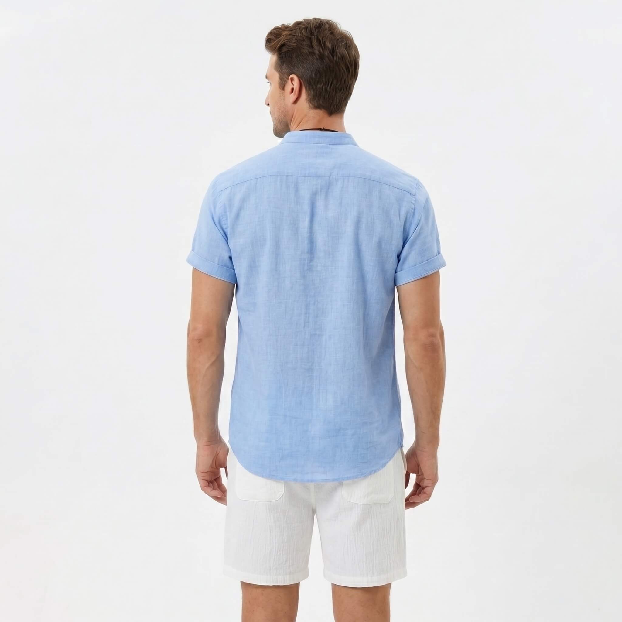 Back view of man wearing light blue linen look stand collar shirt and crinkle drawstring shorts