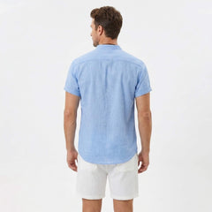 Back view of man wearing light blue linen look stand collar shirt and crinkle drawstring shorts